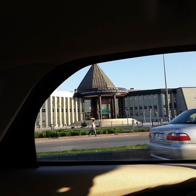 architecture, built structure, building exterior, car, transportation, window, sky, sunlight, land vehicle, road, clear sky, street, day, mode of transport, house, shadow, outdoors, empty, grass, no people