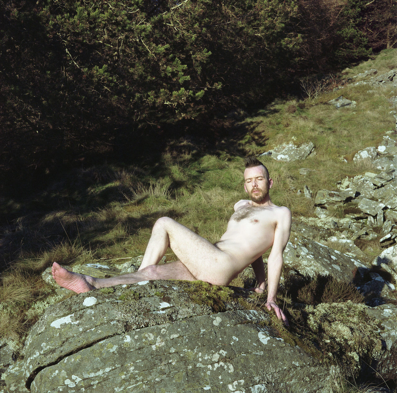 young adult, one person, looking at camera, portrait, rock, shirtless, full length, young men, leisure activity, solid, rock - object, nature, real people, smiling, water, sitting, relaxation, day