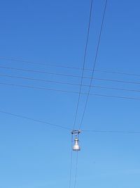 Low angle view of electricity pylon against clear blue sky