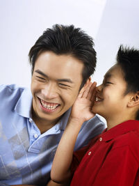 Smiling son whispering in ear of father