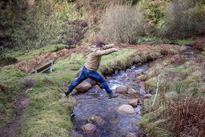 Man jumping over stream in forest
