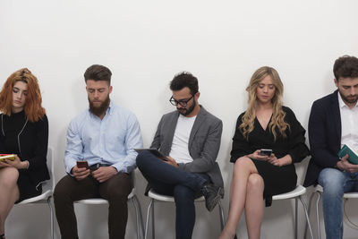 Portrait of smiling friends using digital tablet while sitting on terrace