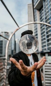 Man levitating crystal ball while standing in city