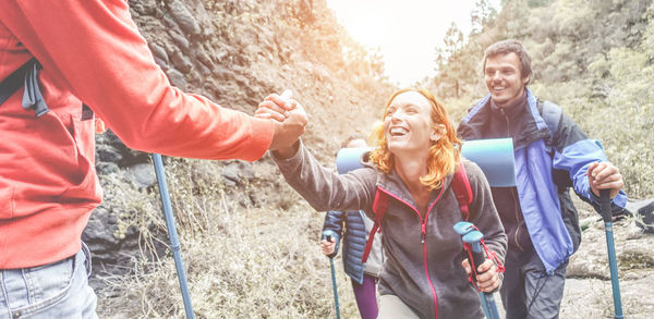 Man giving helping hand to friends while walking on mountain