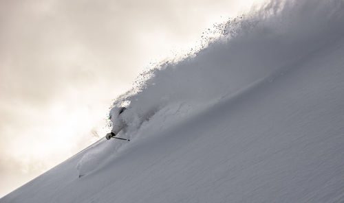 Man skiing on snowcapped mountain against sky