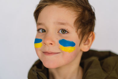 Portrait of a ukrainian boy with a face painted with the colors of the ukrainian flag.