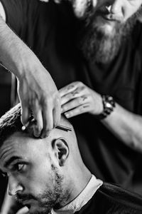 Cropped image of barber cutting man hair in shop