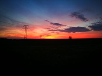 Silhouette of electricity pylon against sky during sunset