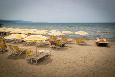 Chairs and tables on beach against sky