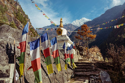 Multi colored flags hanging on mountain against sky