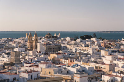 High angle view of townscape by sea against clear sky