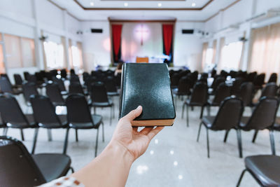Cropped hand of woman holding bible in church
