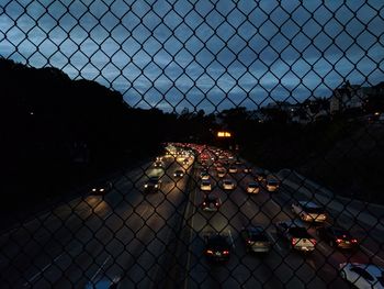 High angle view of cityscape seen through chainlink fence