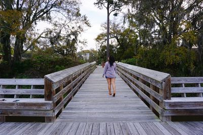 Rear view of woman walking on footbridge