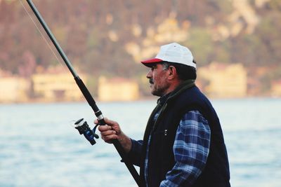 Side view of young man fishing outdoors