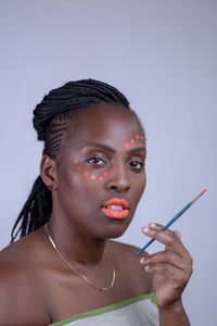 Portrait of woman with face paint against gray background