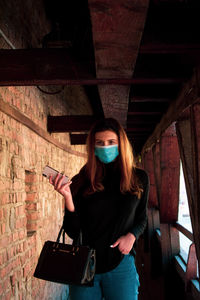 Portrait of young woman standing against wall