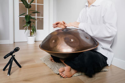 Man playing on hang drum, or steel drum, hangpan, modern steel music instrument at home. recording