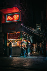 People walking on illuminated street at night