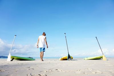 Man walking by paddleboards against sky at boracay island