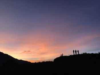 Silhouette people on mountain against sky during sunset