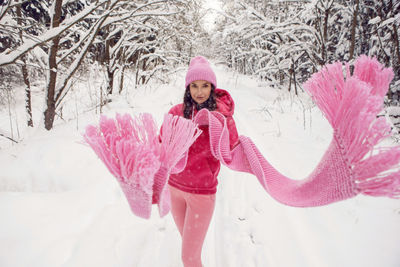 Woman run on a path in the woods in pink clothes a jacket a knitted scarf and a hat forest in winter