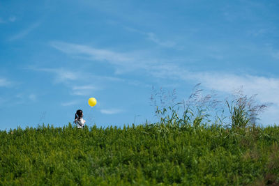 Rear view of woman standing on grassy field against sky