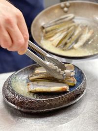Close-up of person preparing razor clams in plate