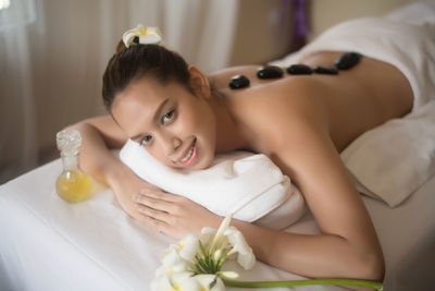 Portrait of smiling young woman lying on massage table in spa