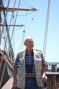 Senior man walking at harbor against clear blue sky