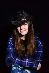 Portrait of girl wearing hat against black background