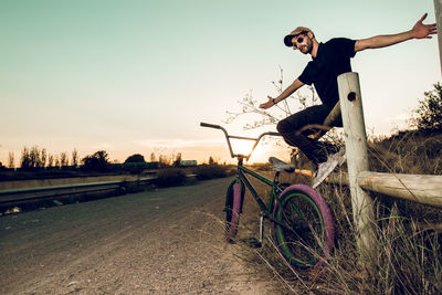 Man riding bicycle on road against sky during sunset