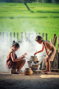 Full length of siblings cooking food outdoors