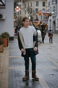 A teenager in winter clothes in full growth looks to the side, winter time in europe without snow