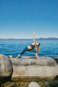 Young woman practicing yoga on lake tahoe in northern california.