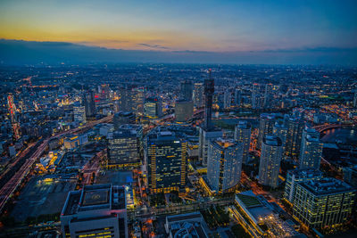 Aerial view of illuminated city buildings against sky during sunset