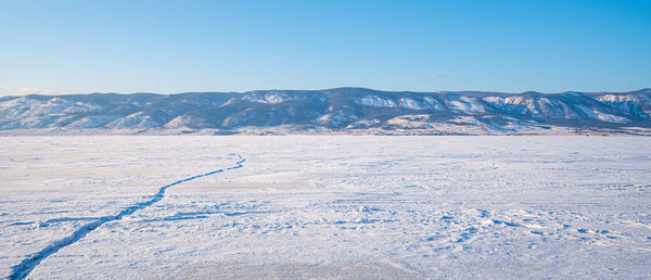 Scenic view of snowcapped mountains against clear blue sky