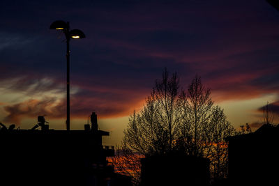 High section of silhouette bare trees against dramatic sky