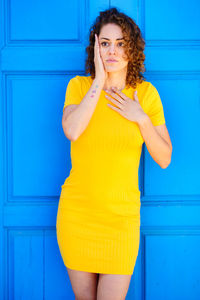 Portrait of young woman standing against wall