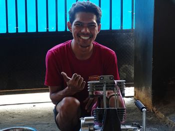 Portrait of smiling young man in front of his motorcycle engine
