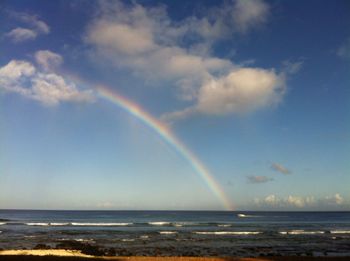 Scenic view of rainbow over sea against sky