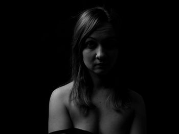 Portrait of young woman against black background