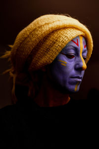 Close-up portrait of woman wearing hat against black background