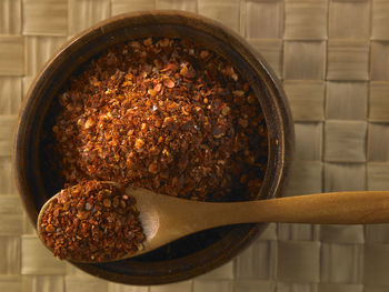 Directly above shot of chili flakes in wooden bowl on table