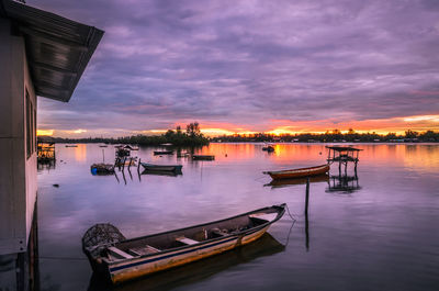 Boats moored at harbor against dramatic sky