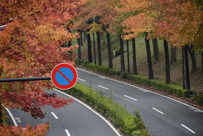 Road sign by trees during autumn