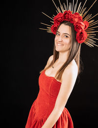 Portrait of smiling young woman standing against black background