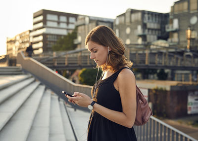 Germany, young woman with smart phone exploring hamburg