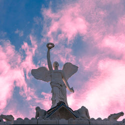 Low angle view of angel statue against sky during sunset