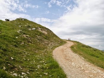 Road passing through landscape against cloudy sky